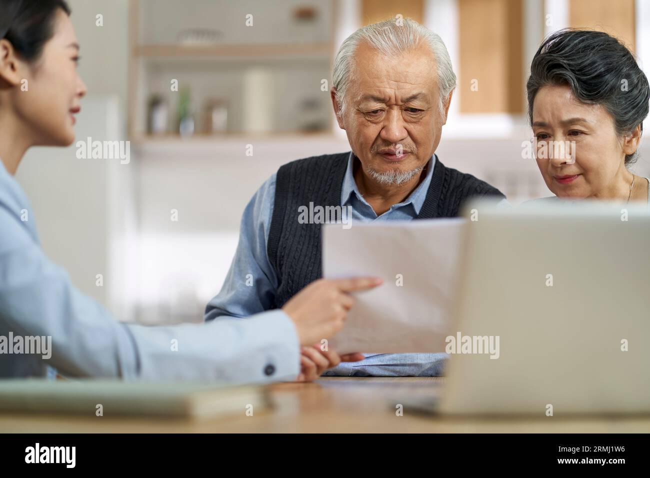 senior asian couple appears confused by and suspicious at a sales person selling financial product Stock Photo
