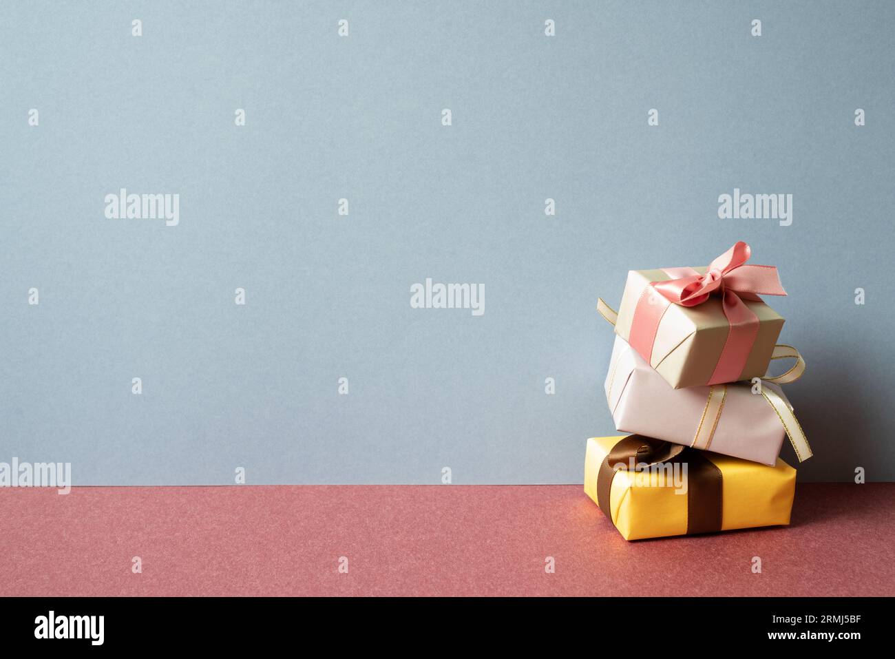 Stack of colorful gift box on red table. gray wall background Stock Photo