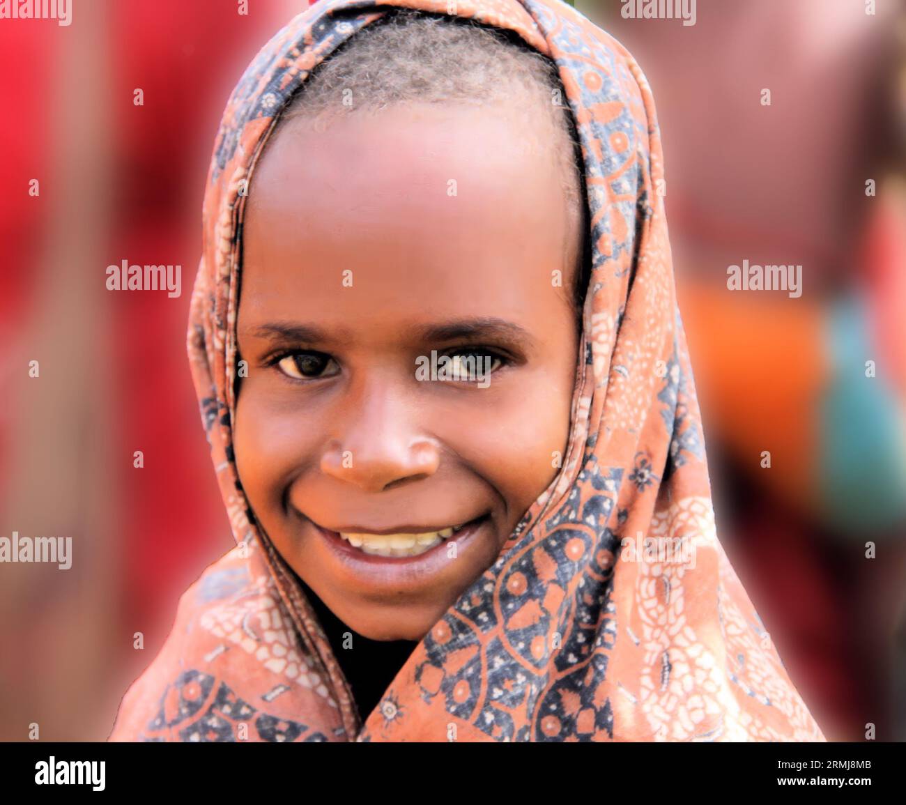 A closeup photo of a young girl in the highlands of Papua, Indonesia, with a cloth covering on her head on a cool day. Stock Photo