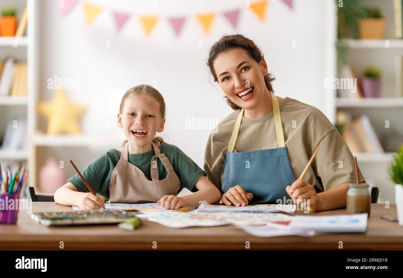 Happy kid and teacher at the art class. Woman and child are painting ...
