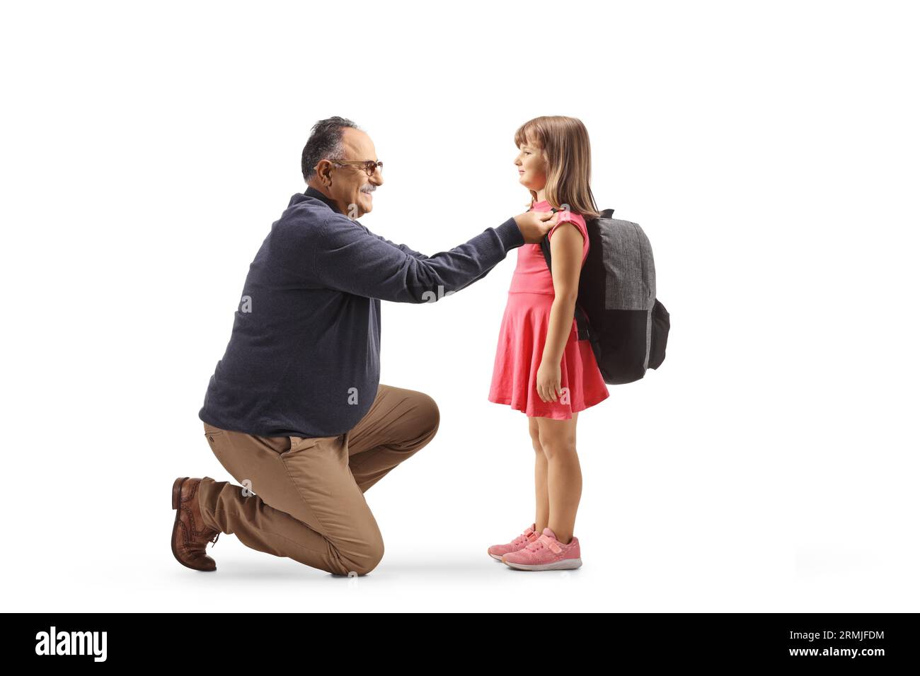 Full length profile shot of a mature man helping a child to put a backpack on isolated on white background Stock Photo