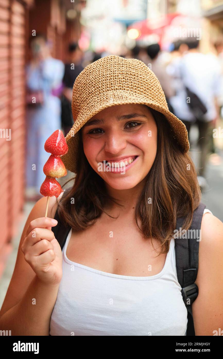 Tourist woman with candied strawberries on a stick in Tokyo, Japan