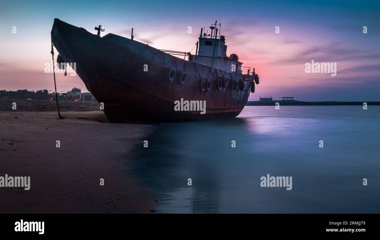 An antiquated vessel docked at the beach at sunset Stock Photo