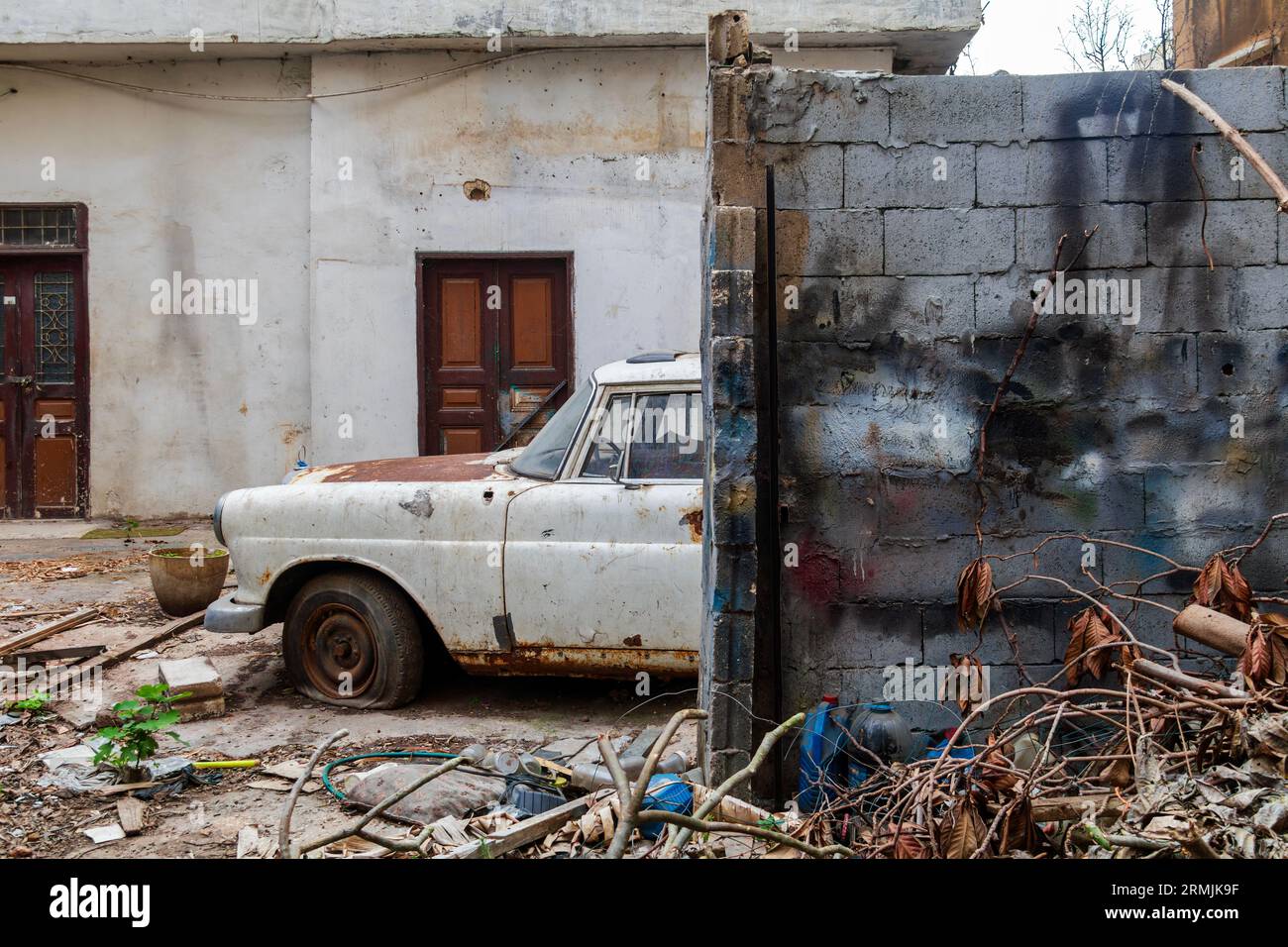 Rusty old car parked next to a brick wall. The car is a Mercedes-Benz W110, and it is in a state of disrepair. Stock Photo