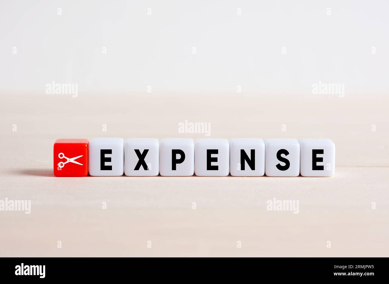 Cutting expenses and costs. Expense reduction and financial stability. Scissors icon and the word expense on cubes. Stock Photo
