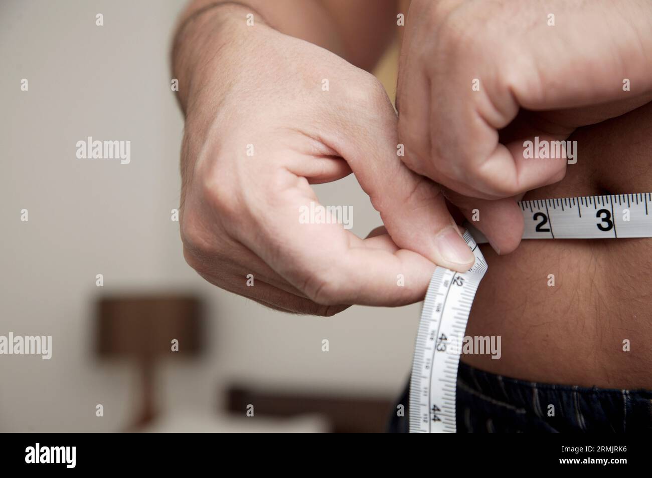 Close up of man measuring waist with tape measure Stock Photo