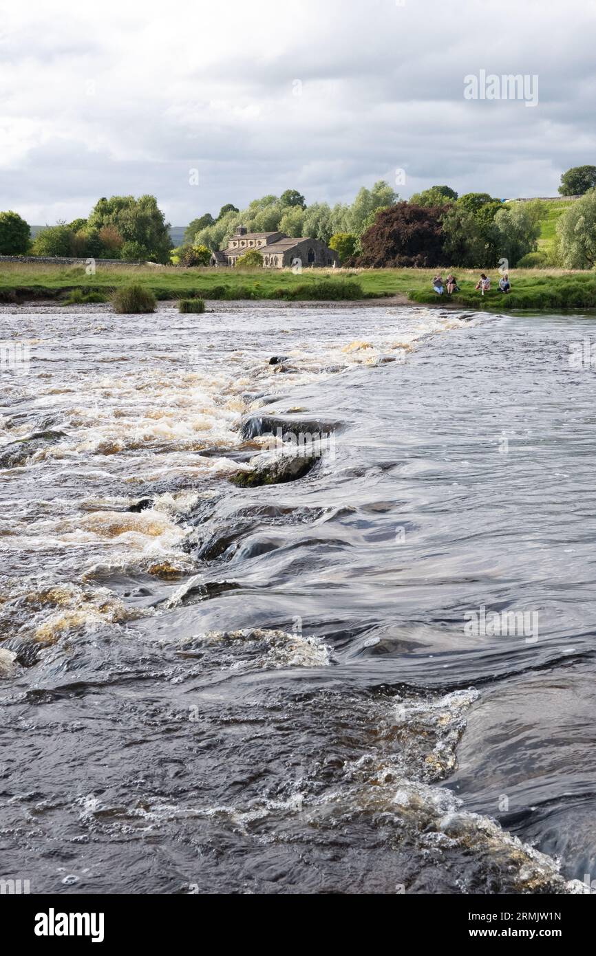 Linton Stepping Stones across the River Wharfe leading to St Michael and All Angels Church - impassable as the river is high, Linton, Skipton, England Stock Photo
