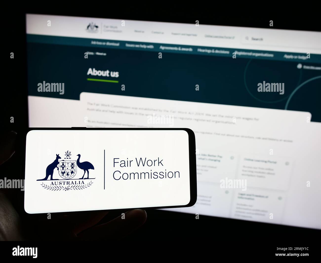 Person holding mobile phone with logo of Australian Fair Work
