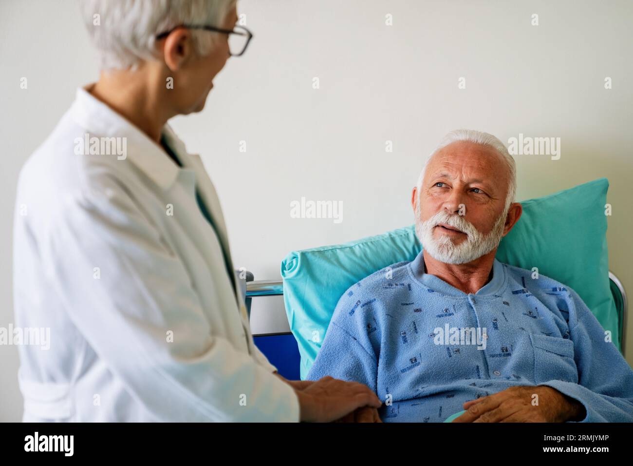 Doctor consulting happy senior man patient on hospital bed. Healthcare ...