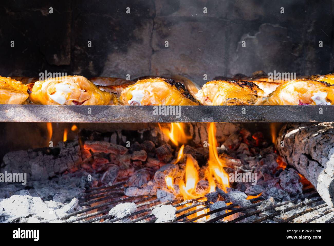 Barbecue grill pit with hot coals cooking chicken. Glowing and flaming charcoal briquettes for fire BBQ. Stock Photo