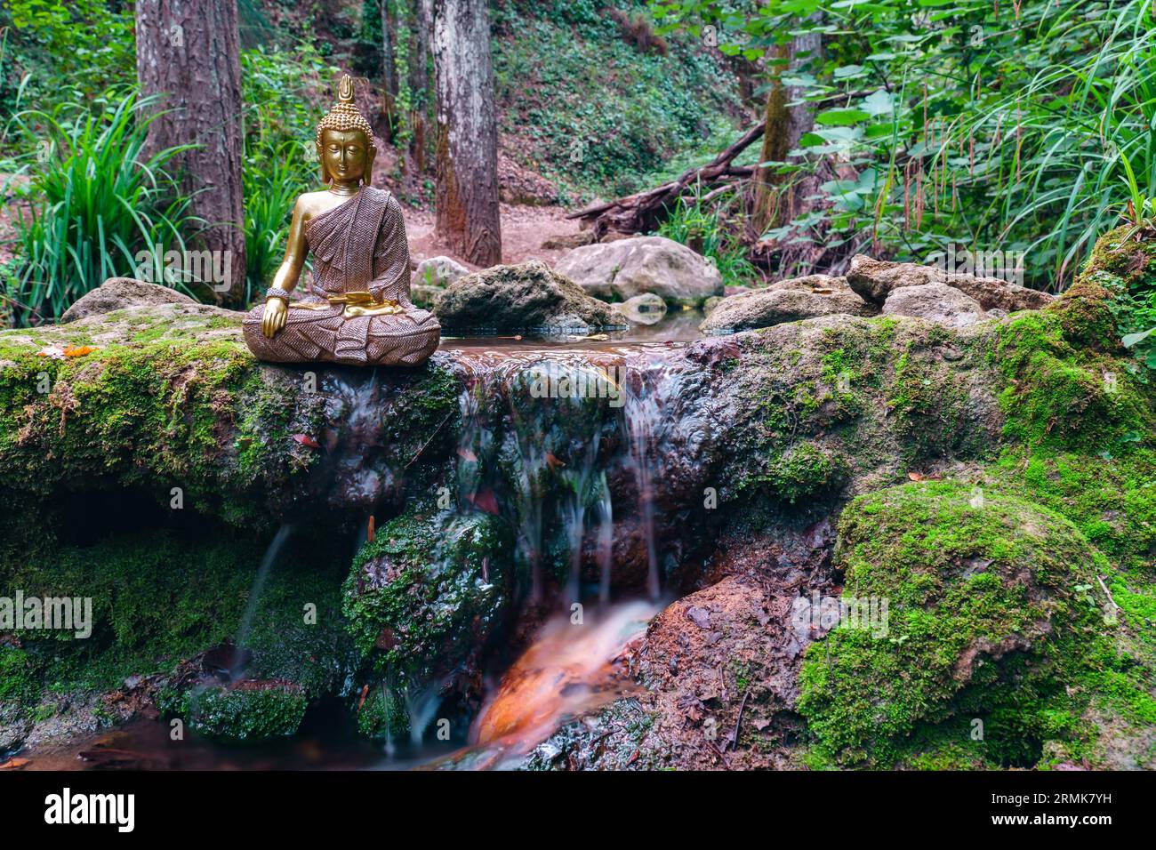 Buddha statue sitting in a mountain river meditating on a waterfall