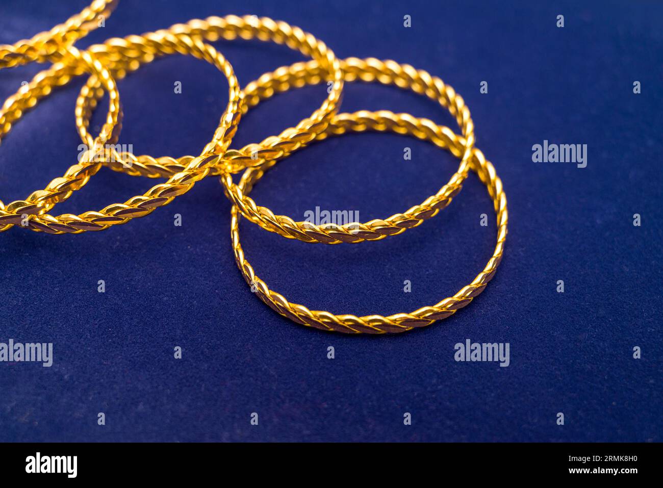 24k (24 carat) Turkish gold twist bracelet standing in a heap on a dark blue background in the gold store Stock Photo