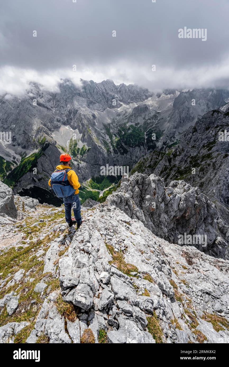 Mountaineer at the summit of the Waxenstein, view over rocky and narrow ...