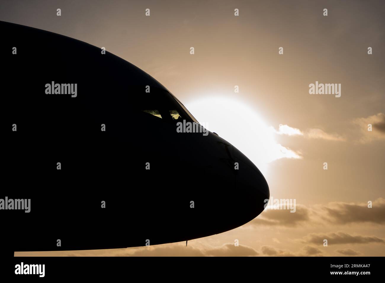 Silhouette of the front profile of a commercial aircraft against a orange setting sun Stock Photo