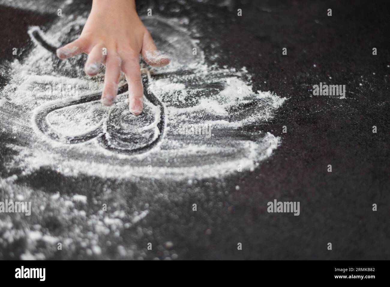 Close up girl s hand drawing heartshape flour Stock Photo