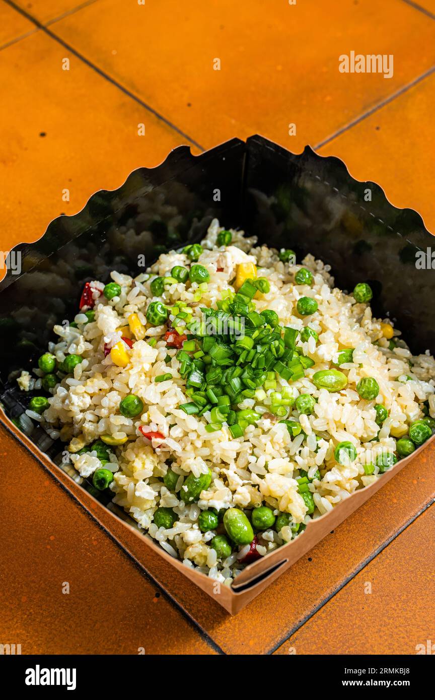 Fried rice with egg and vegetables in box take away. Orange background