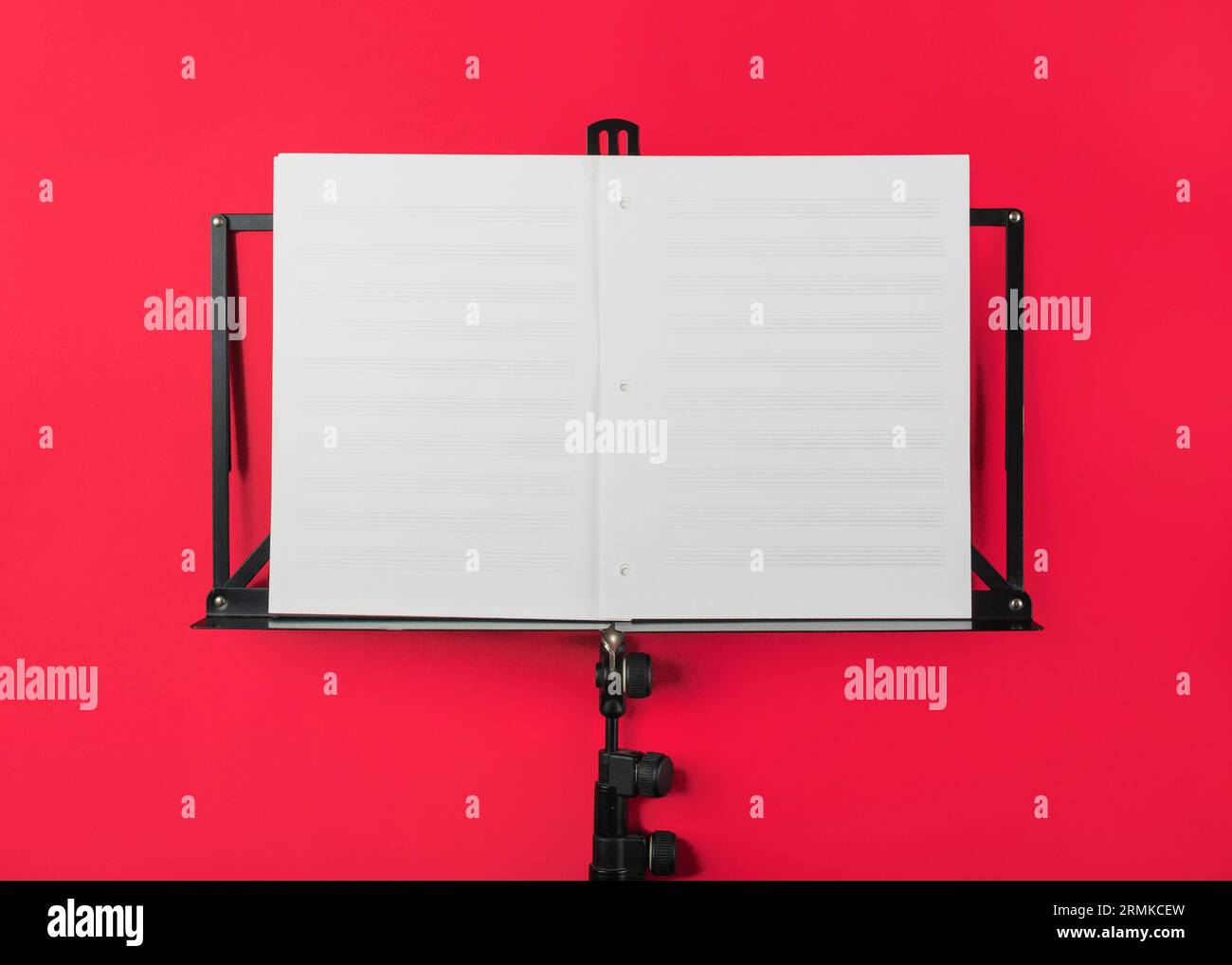 Music stand with blank white musical page red backdrop Stock Photo