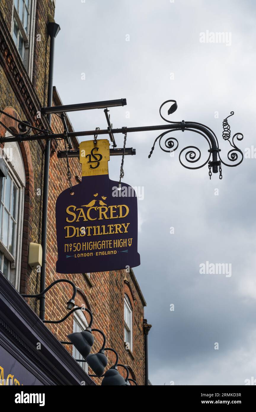 Ornate hanging shop sign above the Sacred Distillery, Bottle Shop & Tasting Room on Highgate High Street, Highgate Village, London, England, UK Stock Photo
