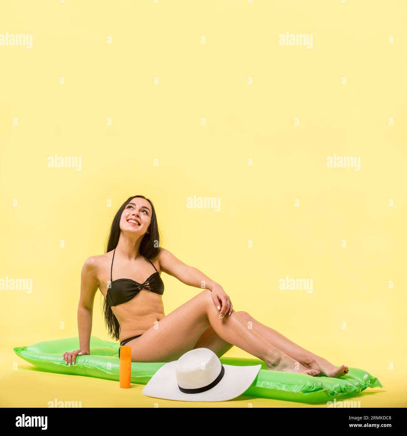 Woman black swimsuit sitting water mattress smiling Stock Photo