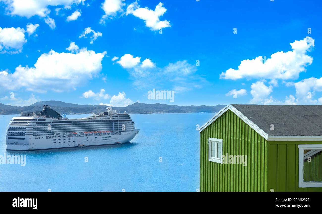 Cruise ship visit to Greenland city Qarqotoq with colored houses located near fjords and icebergs. Stock Photo