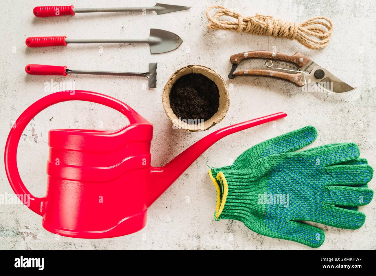 Gardening equipment watering can peat pot secateurs rope gardening gloves concrete backdrop Stock Photo