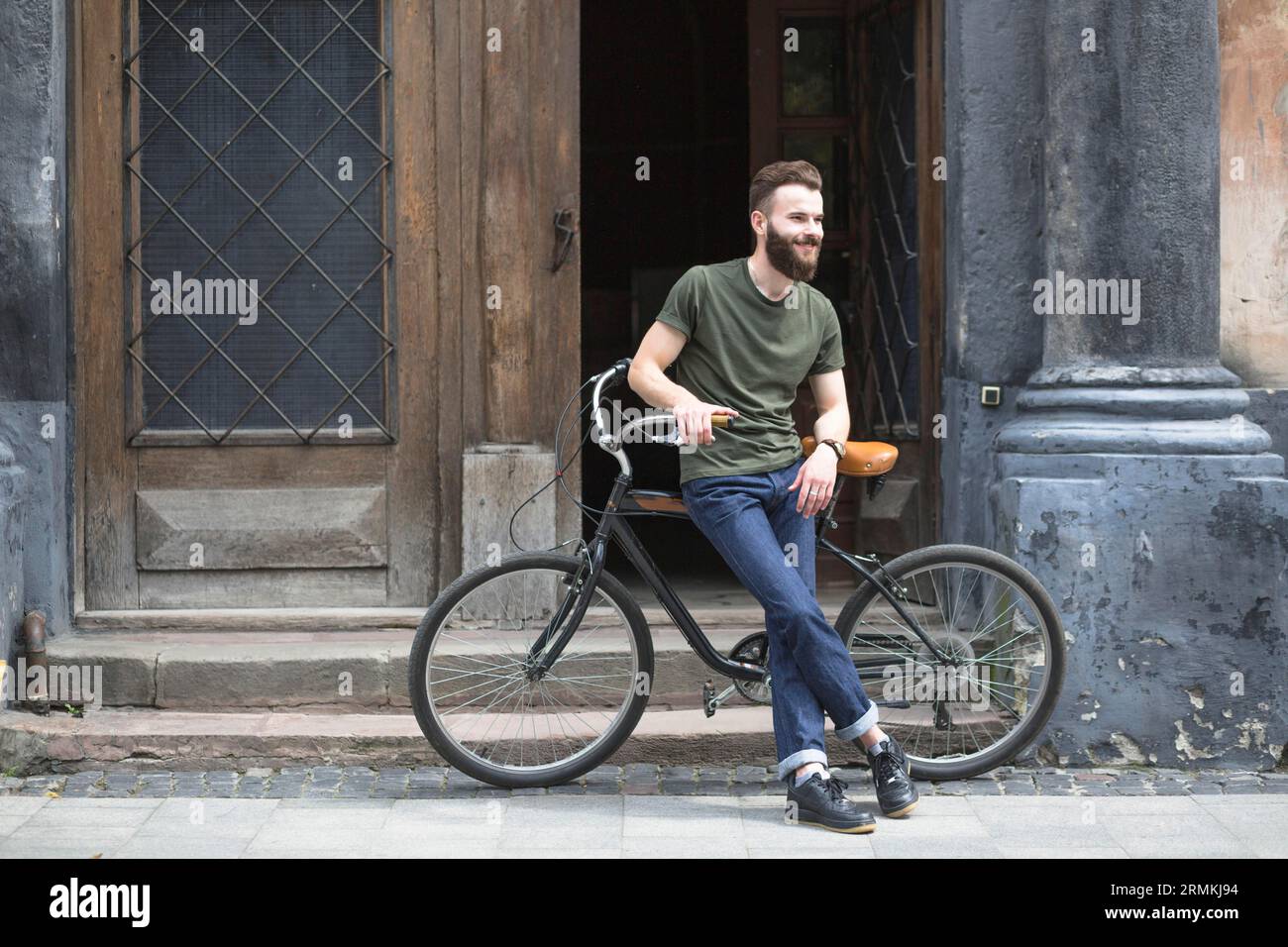 Man sitting bicycle front open door Stock Photo Alamy
