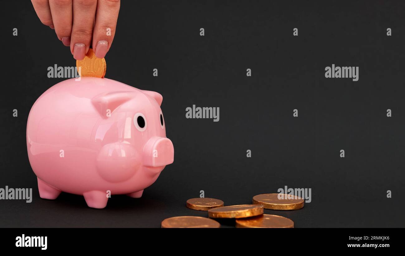 Person putting pink piggy bank coins Stock Photo