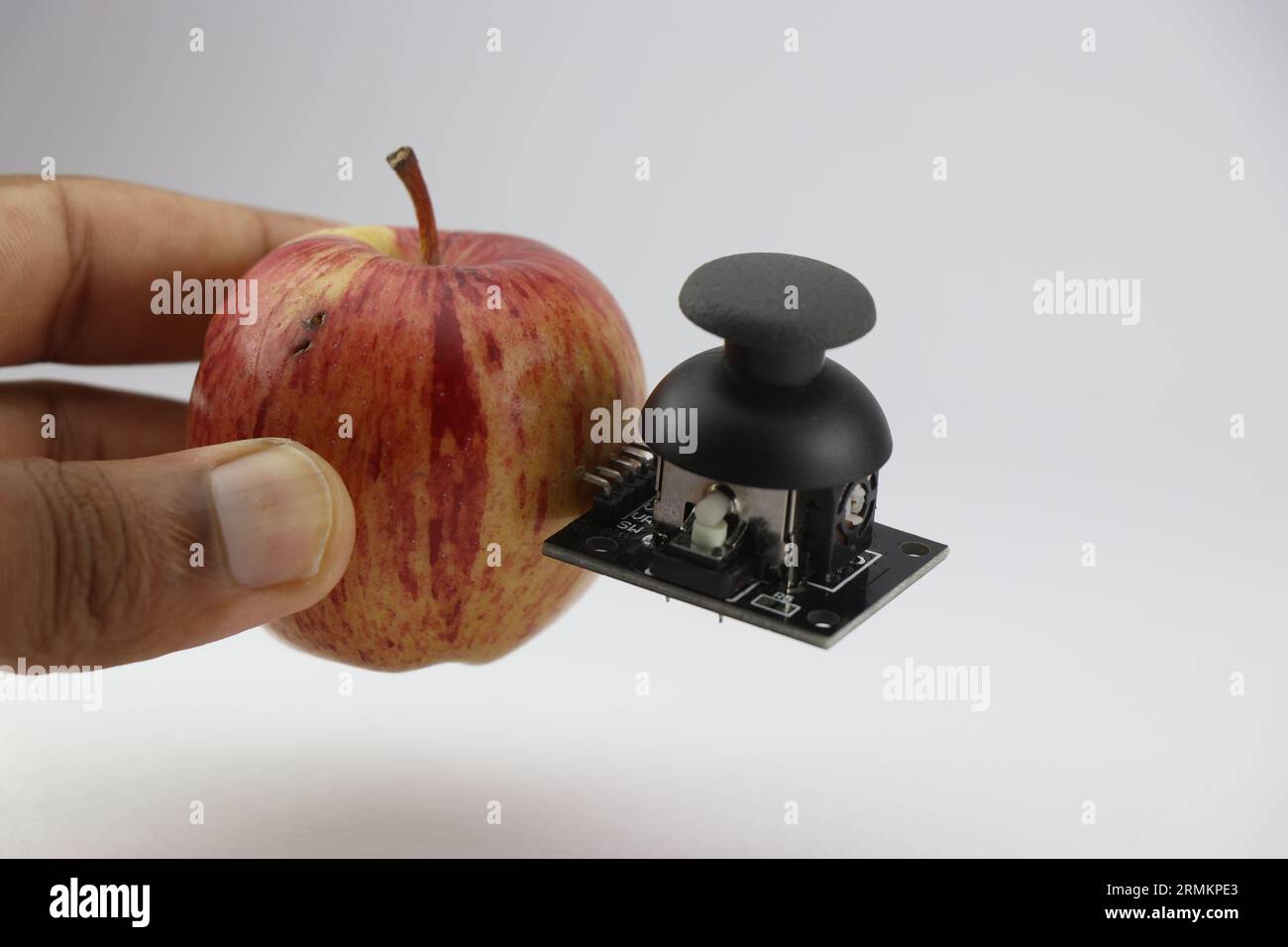 Apple with joystick module attached showing the concept of integrating technology with organic world Stock Photo