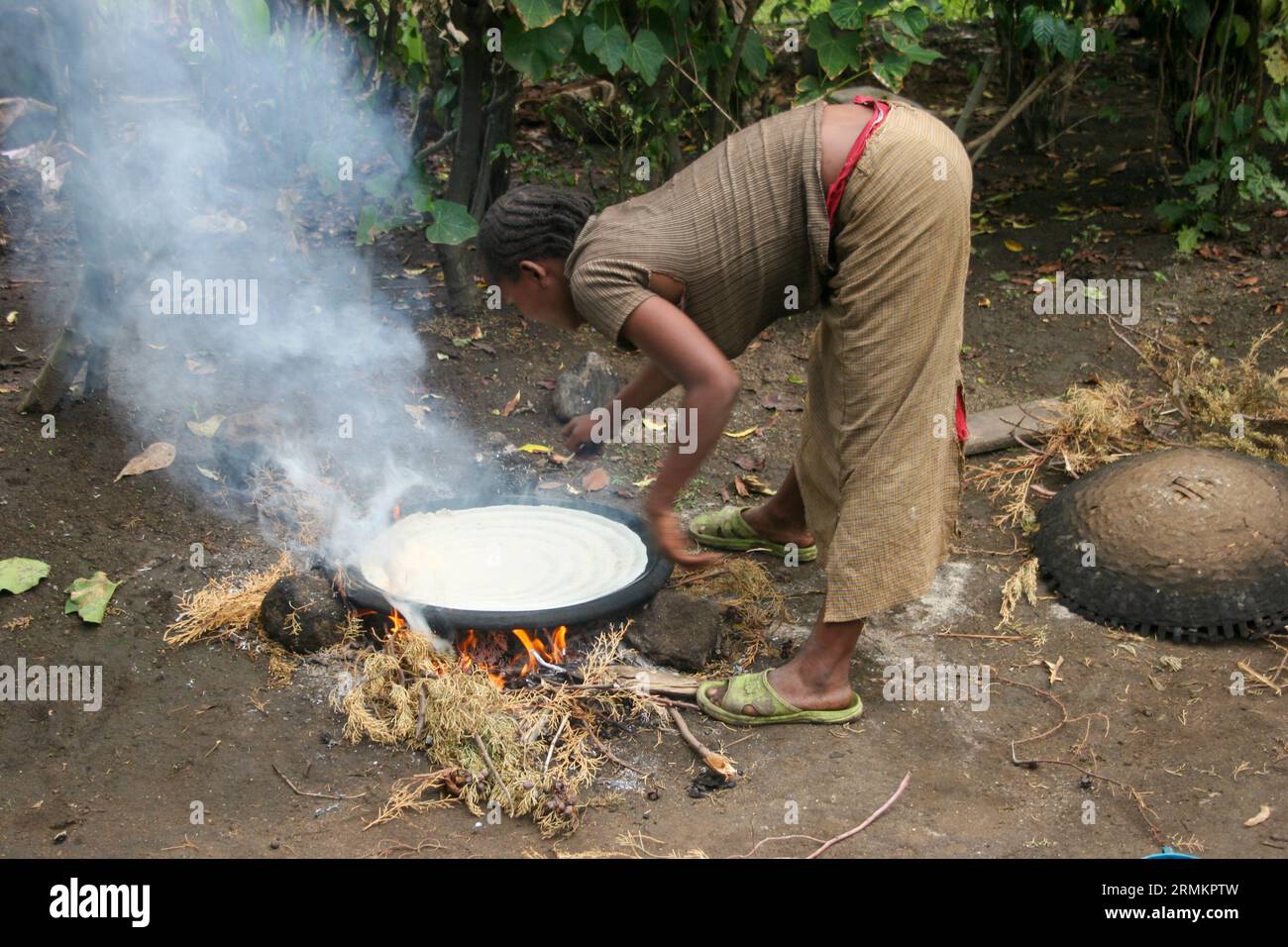 Woman cooking Injera (pancake like bread) on a mogogo over a fire at the market town of Jinka, Omo Valley, Ethiopia Stock Photo
