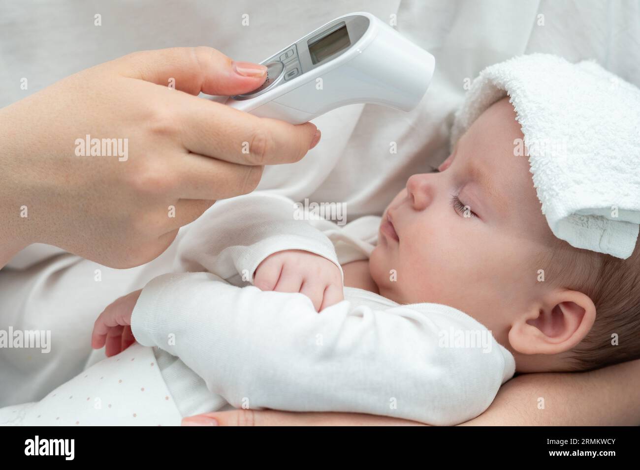 Mother checks newborn's temperature with thermometer. Concept of modern