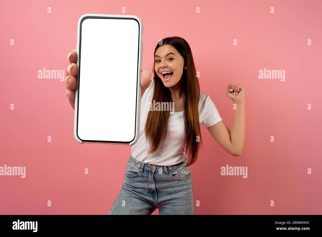 Emotional teen girl holding blank smartphone and celebrating success, mockup Stock Photo