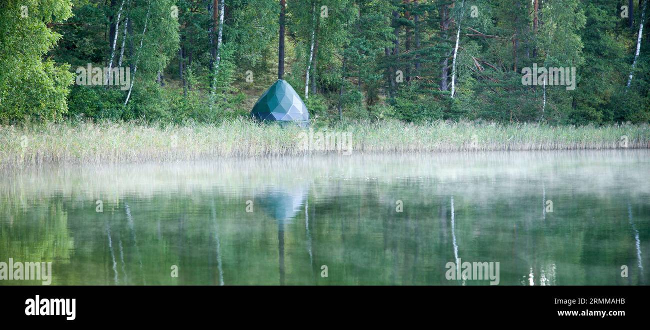 The panoramic early morning view of Baltis Lake shore with a camping tent (Lithuania). Stock Photo