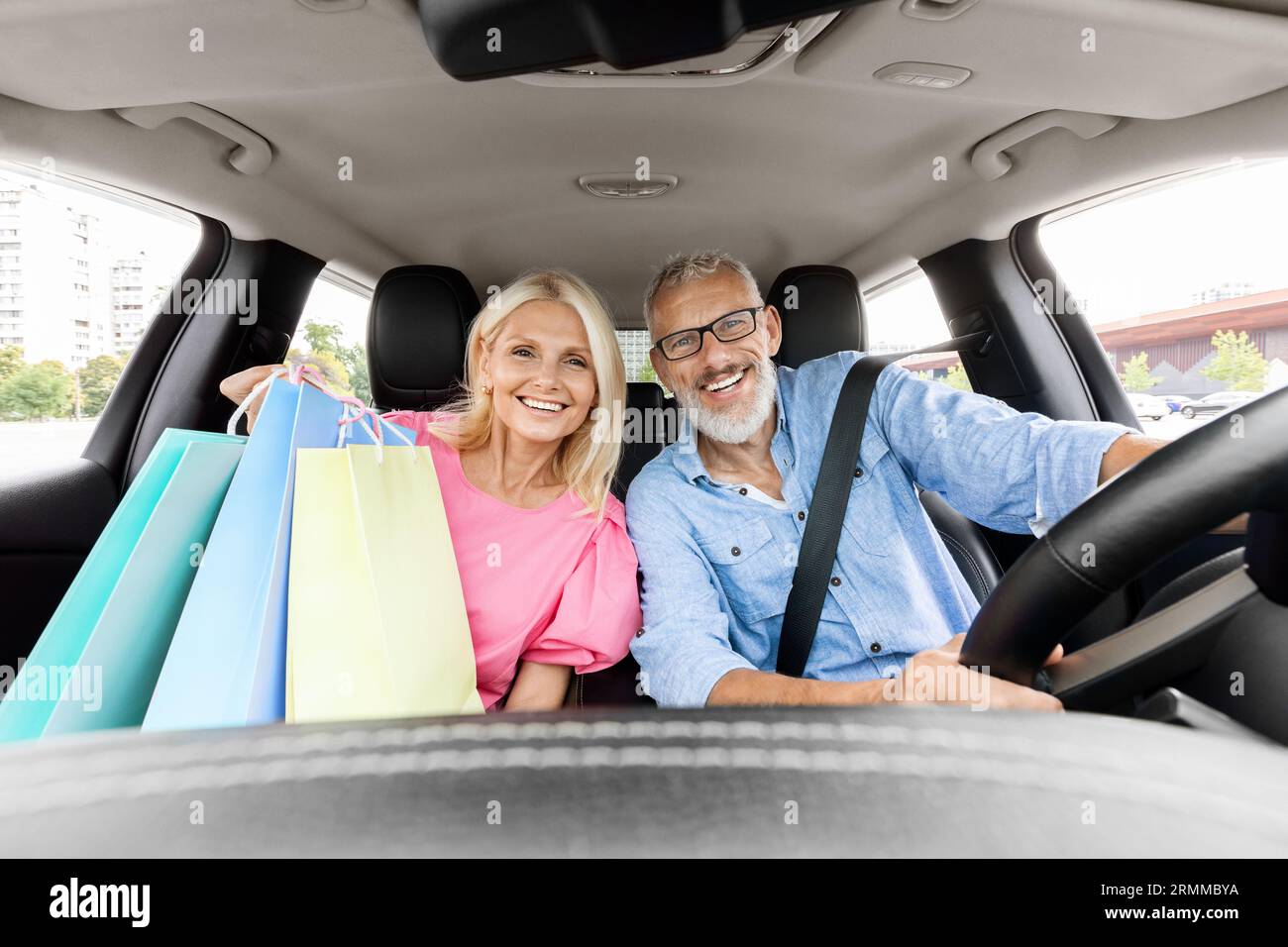 Cheerful pensioners driving home after shopping in mall, talking, smiling Stock Photo