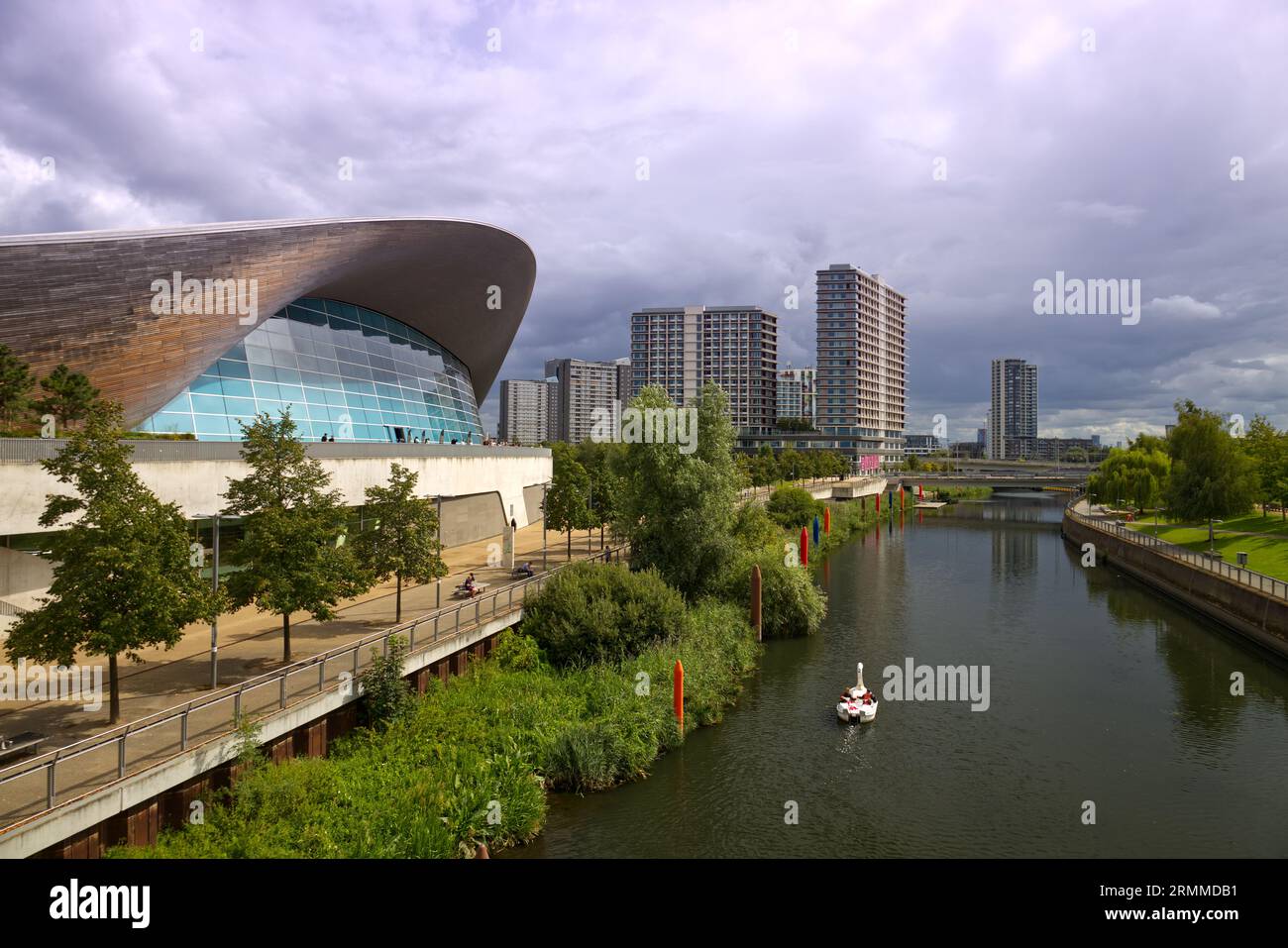 A pedalo on Waterworks river sails past the London Aquatics Centre at Queen Elizabeth Olympic Park, Stratford, London, UK. Stock Photo