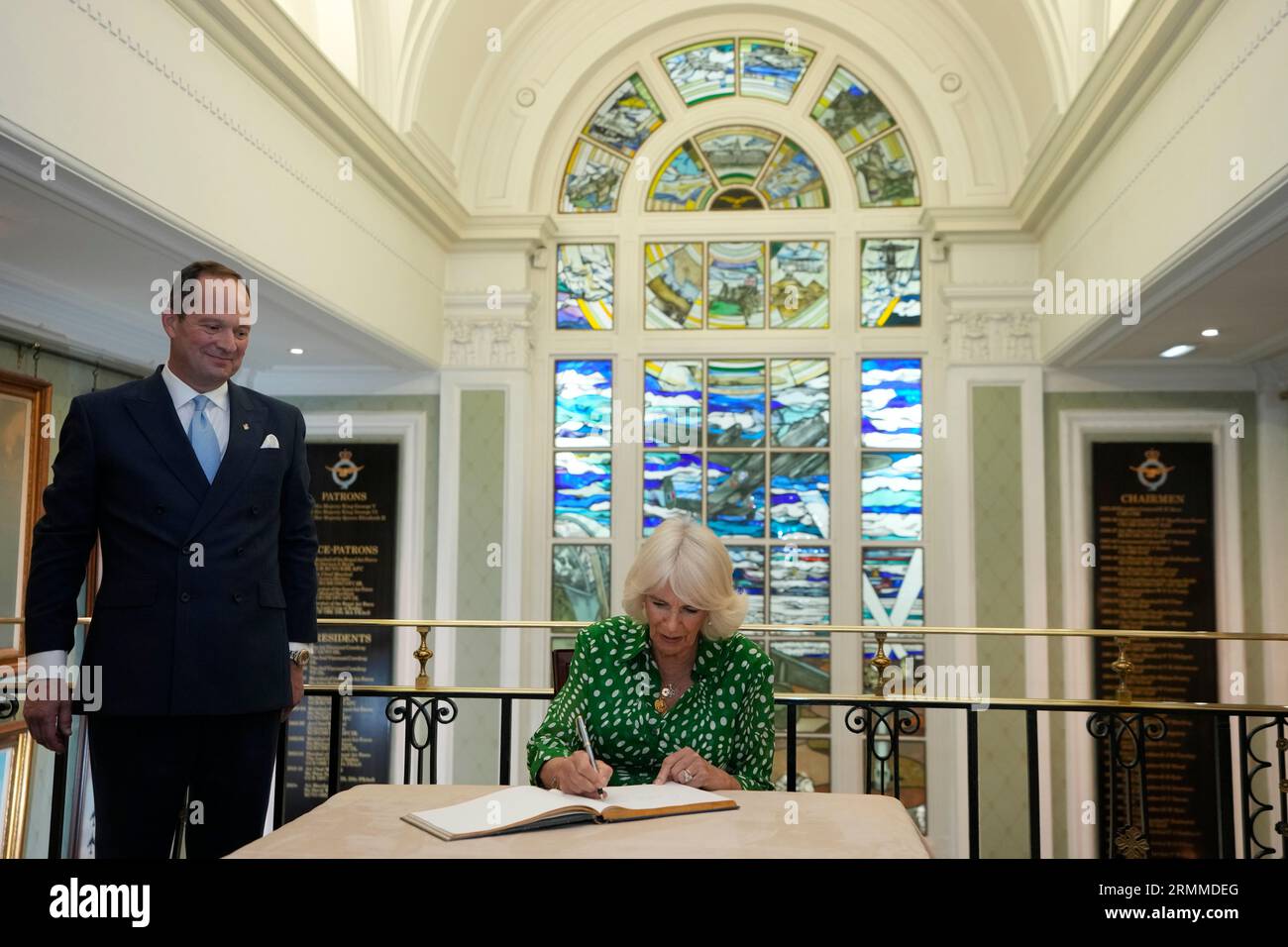 Queen Camilla signs the visitors book alongside club president Miles Pooley during a visit to the Royal Air Force Club in Piccadilly, central London, where she unveiled a portrait of Special Operations Executive (SOE) Operative, Noor-un-Nisa Inayat Khan GC, and formally announced the naming of a room in her honour. Picture date: Tuesday August 29, 2023. Stock Photo