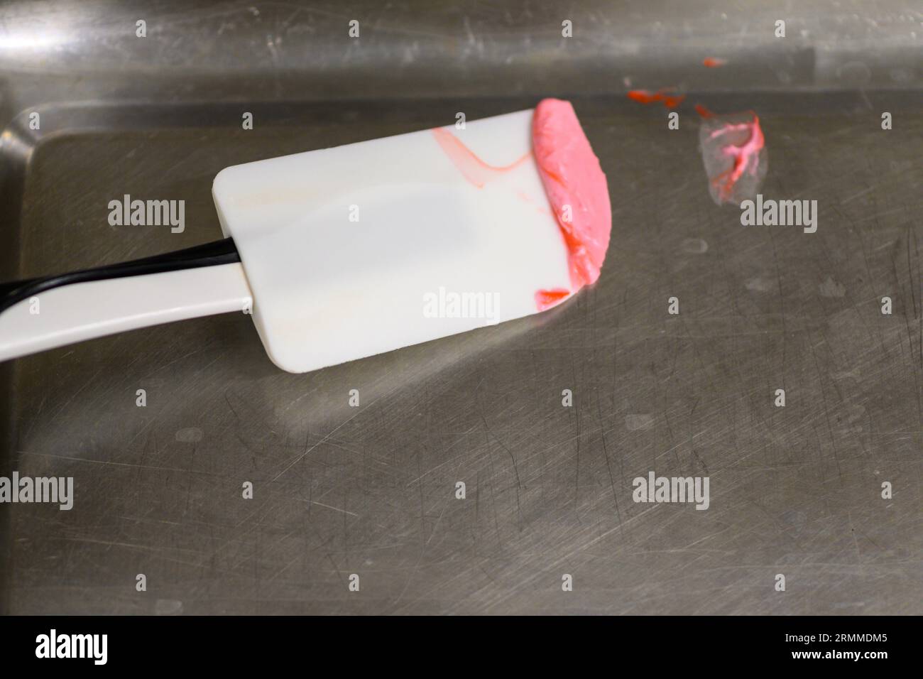 pastry chef styr red butter cream for cake decoration in professional kitchen Stock Photo