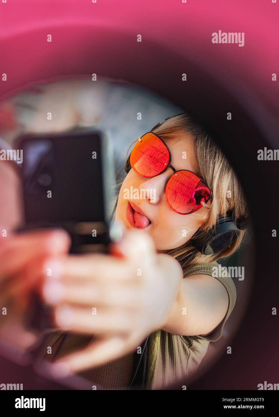 Teenage girl social media blogger recording video speaking looking at smartphone on tripod with ring light, on the balcony of the building. Stock Photo