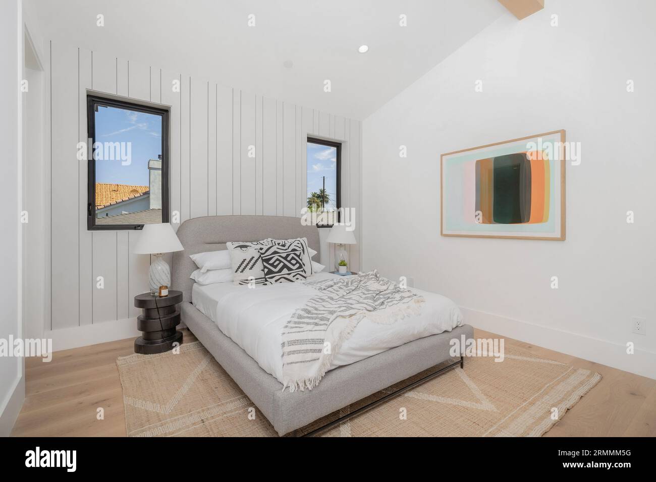 A modern, neutral bedroom featuring a centered double bed with white
