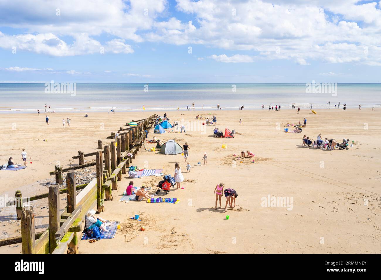 Hornsea beach with wooden groynes and people sunbathing on the large sandy beach at Hornsea East Riding of Yorkshire England UK GB Europe Stock Photo