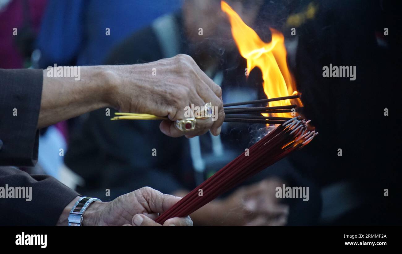 Hands holding and burning incense to perform traditional rituals Stock ...