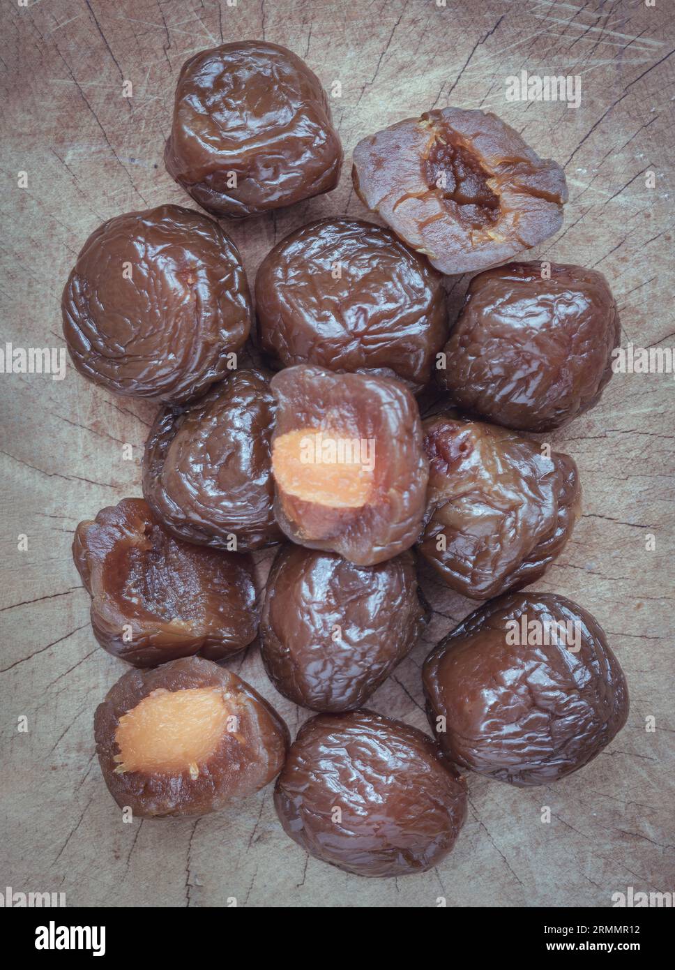 Close-up of Flavored preserved chinese plums (Preserved fruits) on wooden background. Its flavour has sour, salty and sweet taste. Space for text, Sel Stock Photo