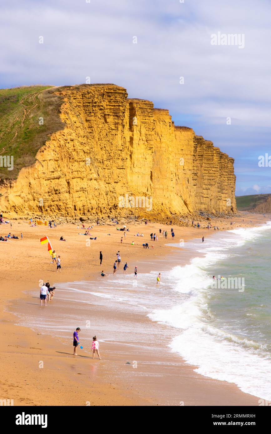 West Bay Dorset, beach and cliffs, and people on the beach in summer; West Bay, Dorset UK Stock Photo