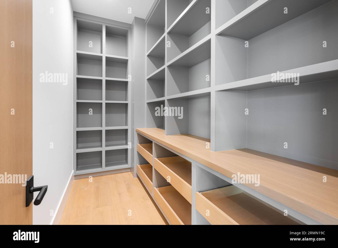 Picture of A spacious white-walled closet with wooden shelves and open shelving ...