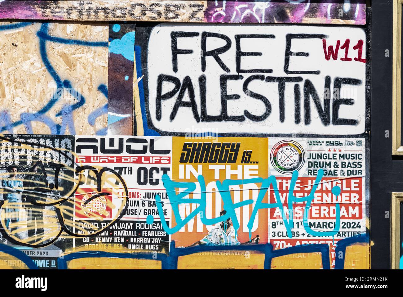 Free Palestine protest sign in the design of a W11 street sign in Notting Hill, London, UK. Event posters and graffiti on wall. Shaggy is on the road Stock Photo
