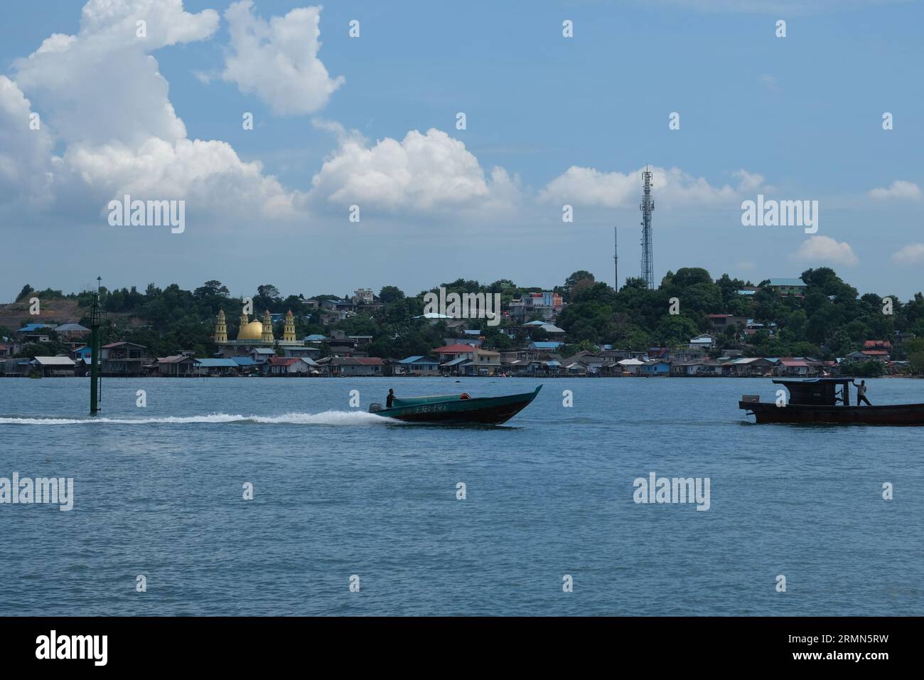 A speedboat on the water with a mosque in the background near the Nagoya ferry terminal in Batam island, Indonesia. 02/10/2022 Stock Photo