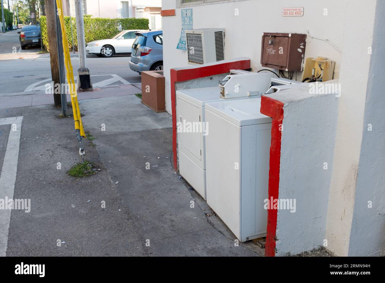 An aged washing machine sits beside a wall of a building Stock Photo