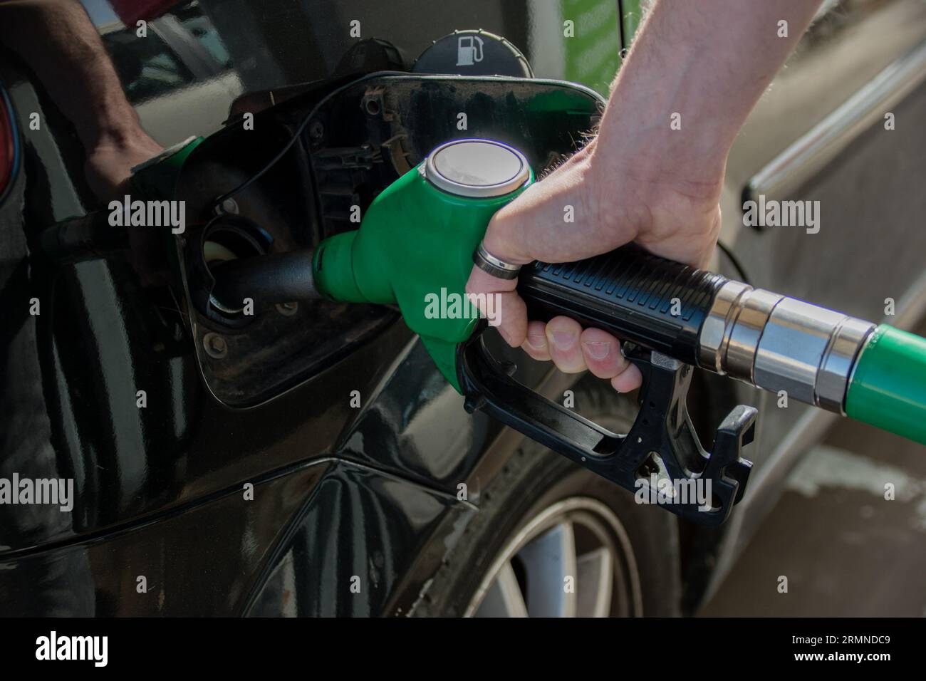 Overhead close-up of a Caucasian man's hand refueling his car with unleaded fuel Stock Photo