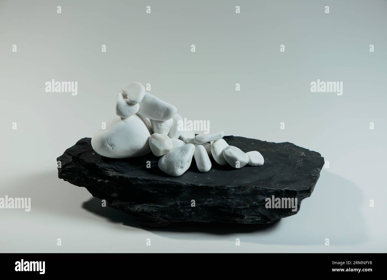 white smooth stones randomly lie over one black flat stone Stock Photo