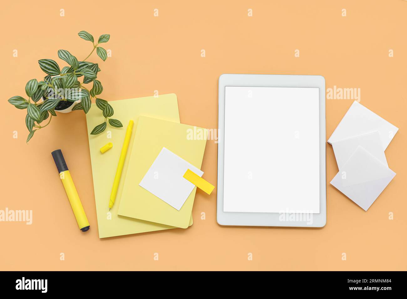 Tablet with notebooks and sticky notes on orange background Stock Photo
