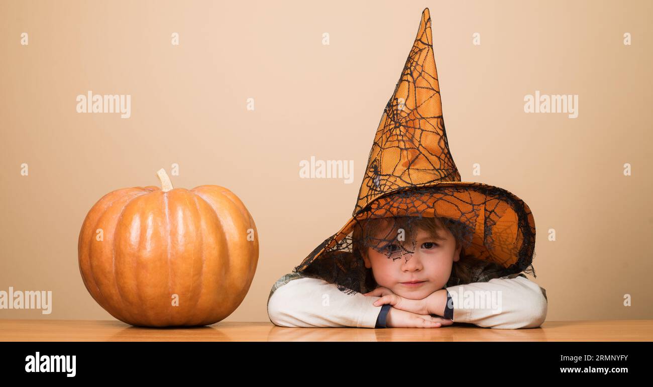Happy Halloween. Smiling boy in witch hat with halloween pumpkin. Halloween kid in magic hat. Little child in wizard costume with jack-o-lantern Stock Photo
